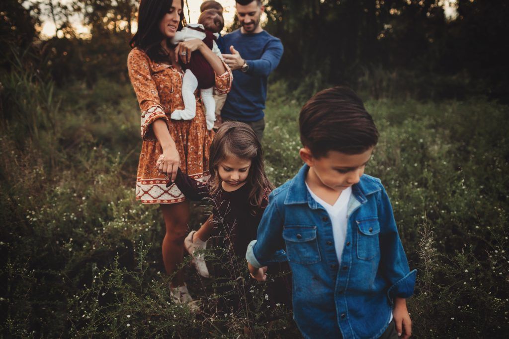 A family is walking through a grassy field.