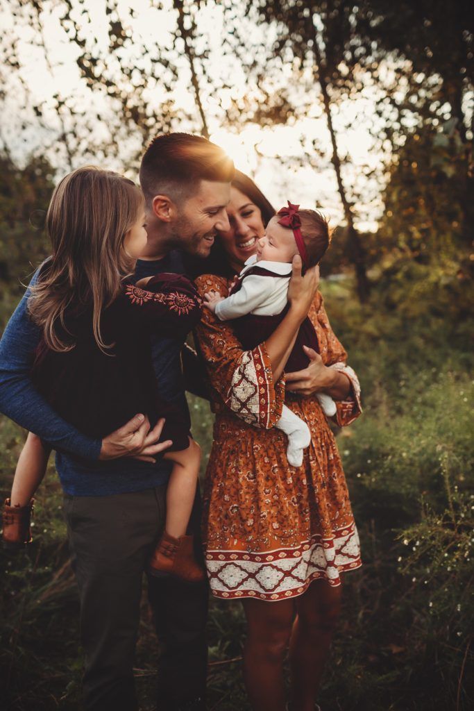 A family is posing for a picture in the woods.