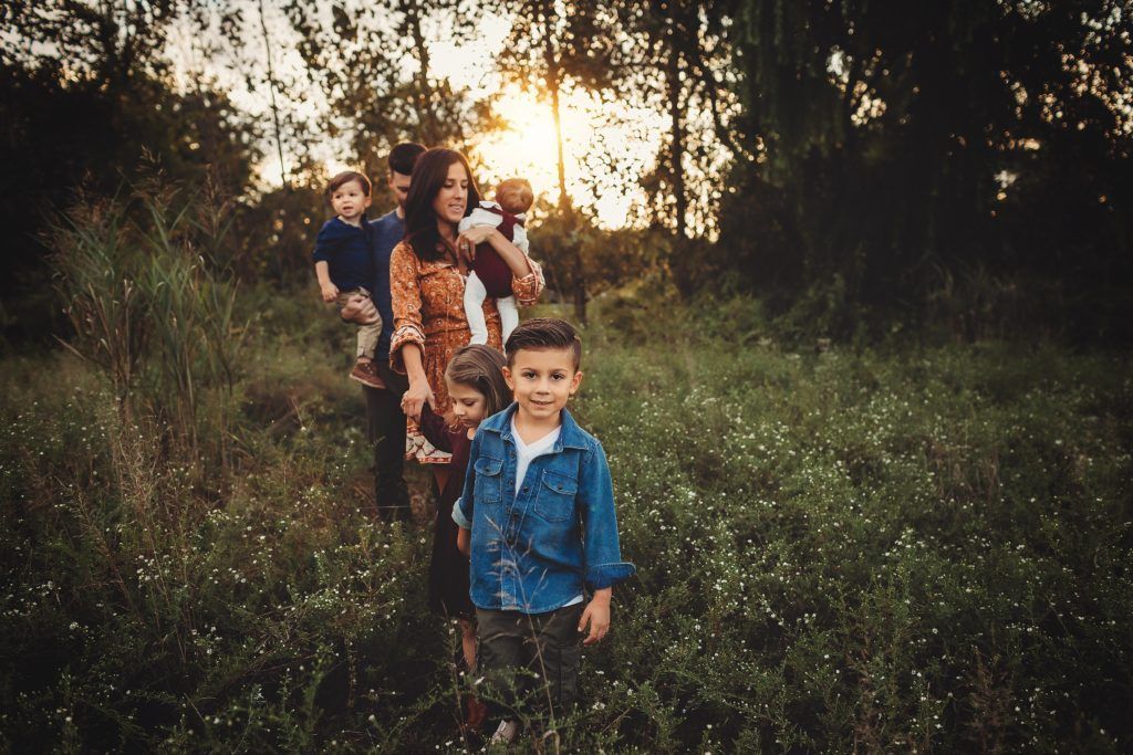 A family is standing in a field with trees in the background.