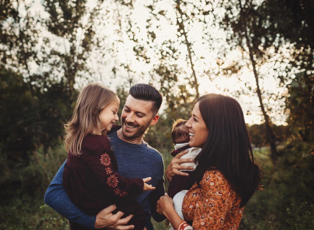 A family is posing for a picture in the woods.