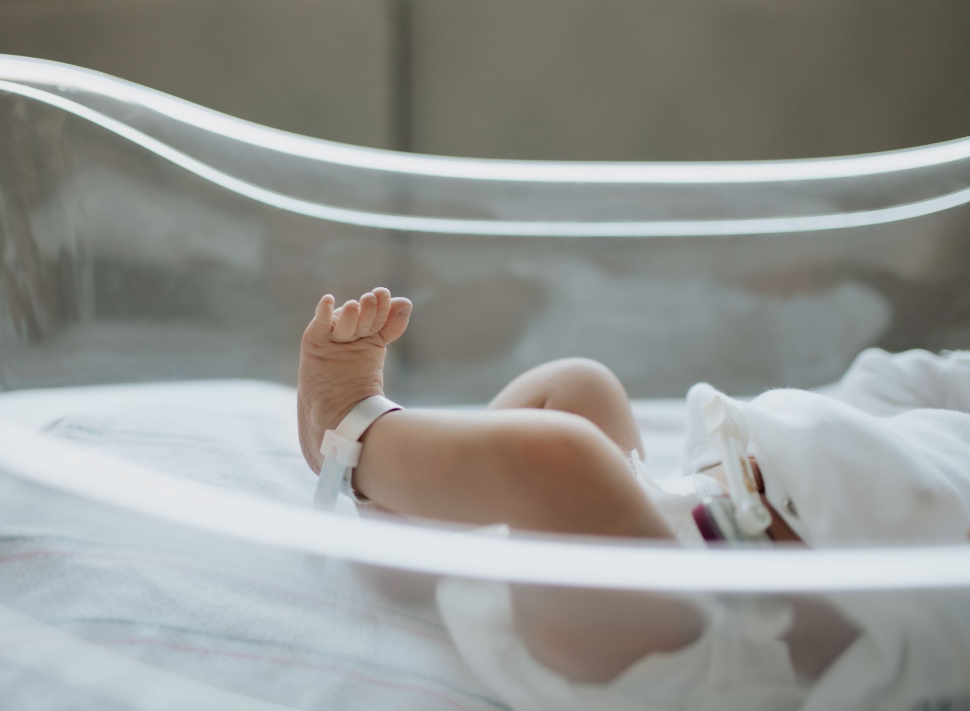 A newborn baby is laying in a hospital bed having pictures taken.