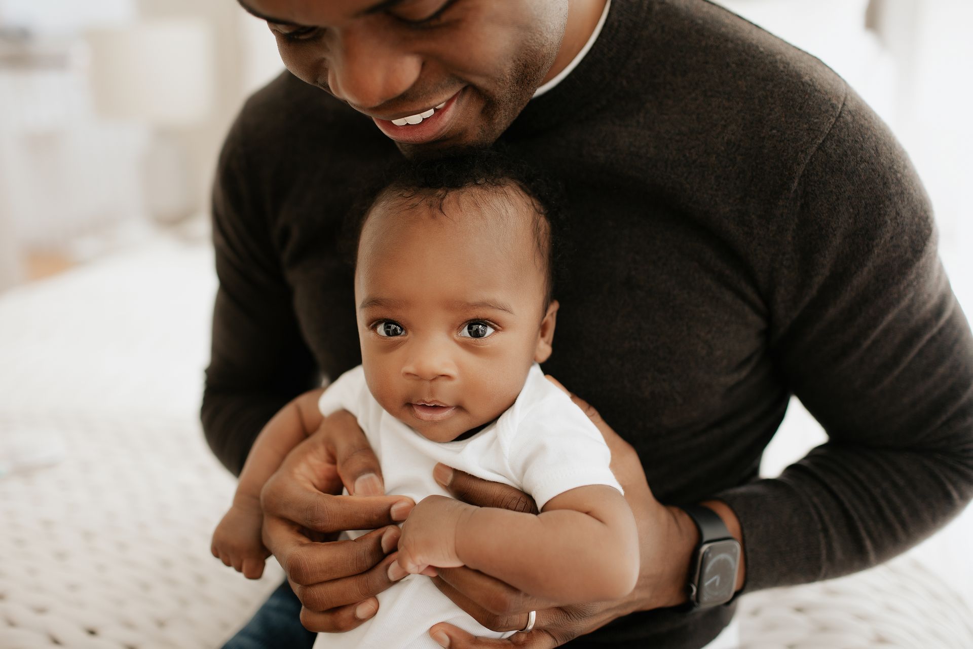 A man is holding a baby in his arms on a bed.