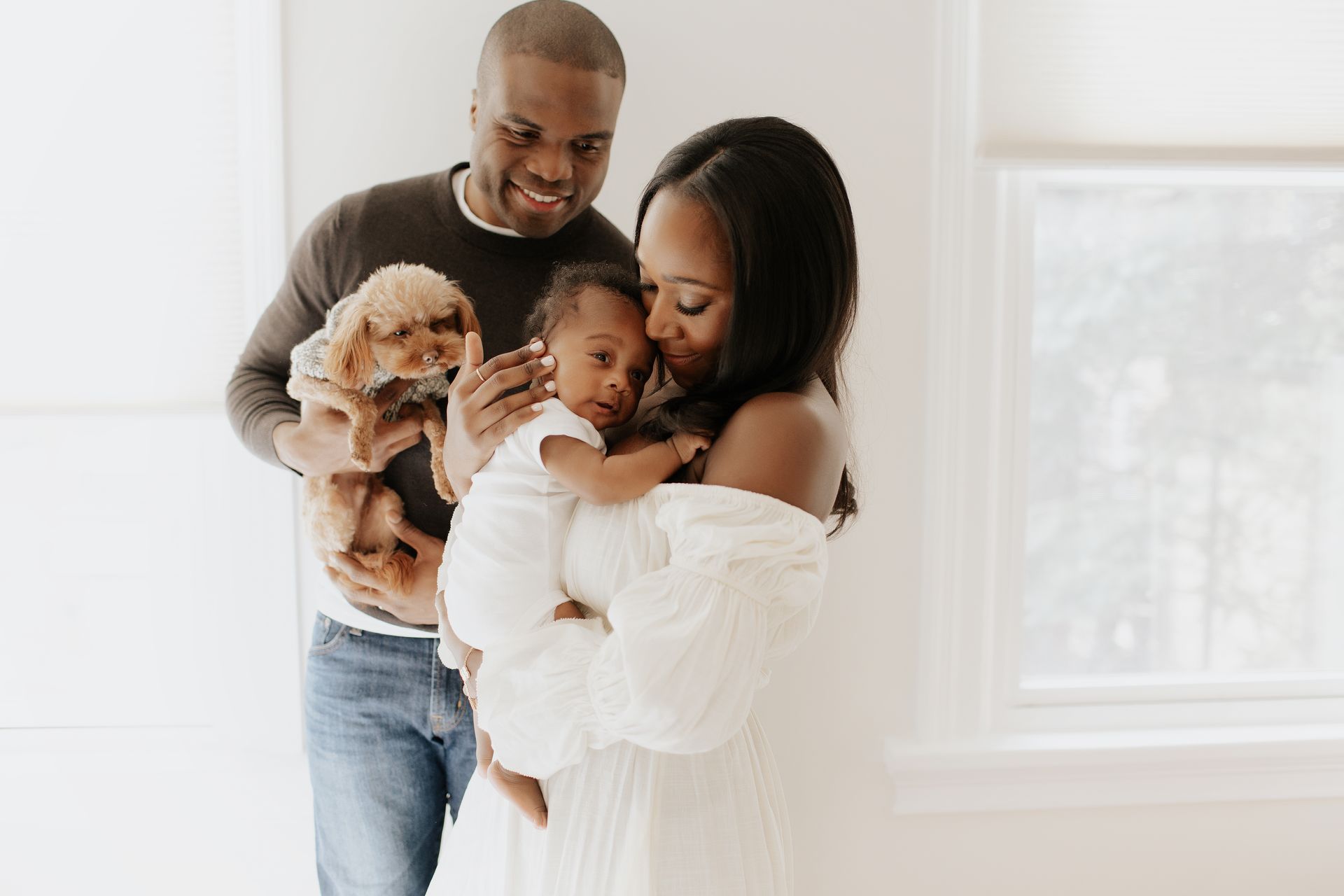 A man and woman are holding a baby and puppy