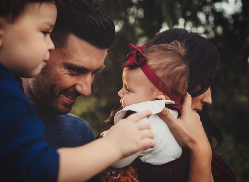 A man and woman are holding a baby girl in their arms.