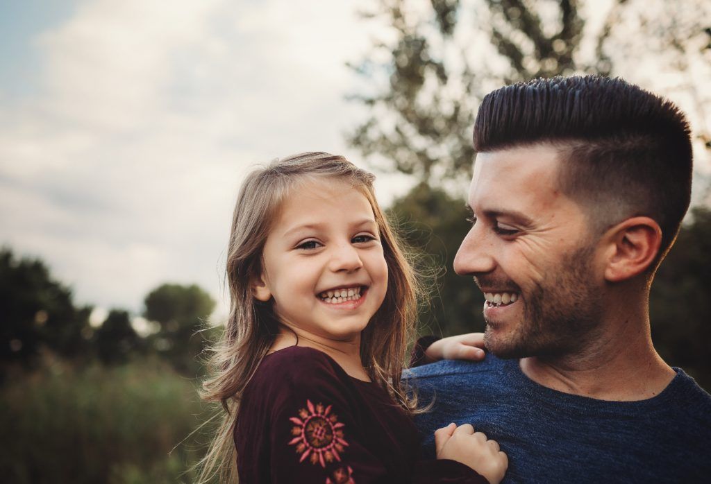 A man is holding a little girl in his arms.