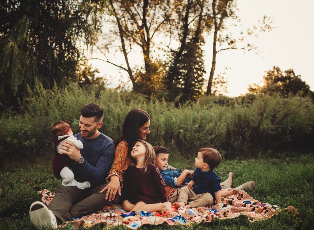 A family is sitting on a blanket in the grass.