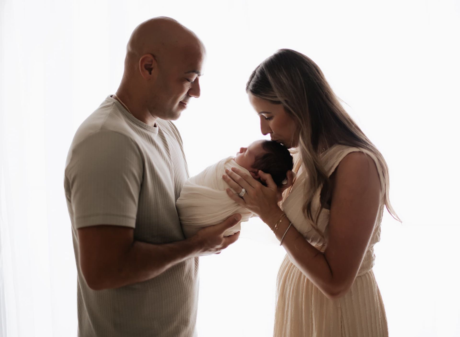 parents holding and kissing newborn baby during Bergen County NJ newborn photography session
