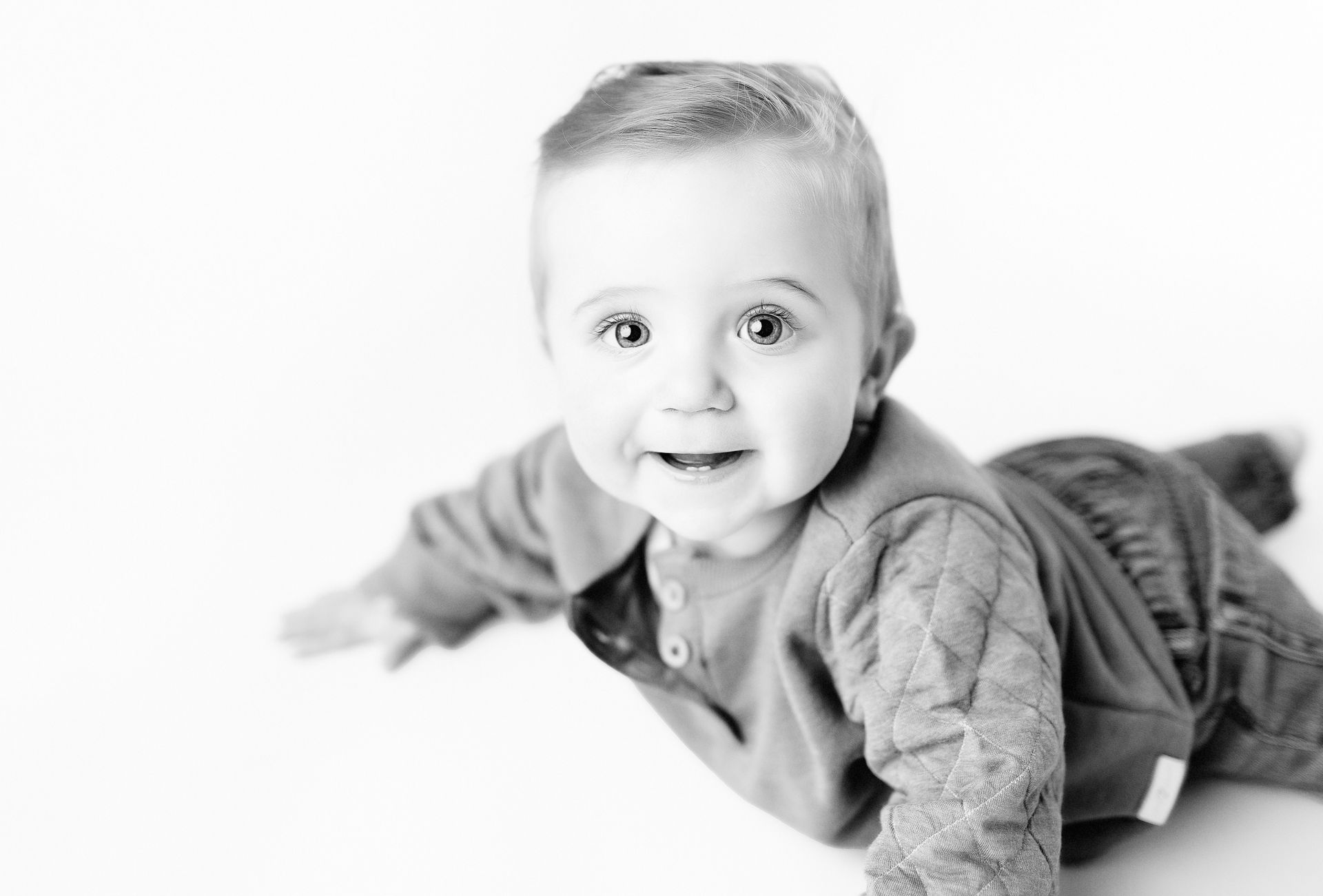 Smiling baby on stomach, reaching forward.