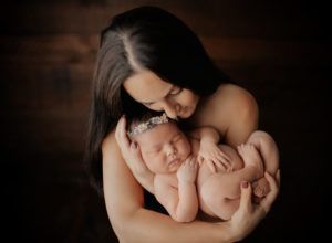 A woman is holding a newborn baby in her arms.