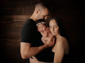 A man and woman are holding a newborn baby in their arms.