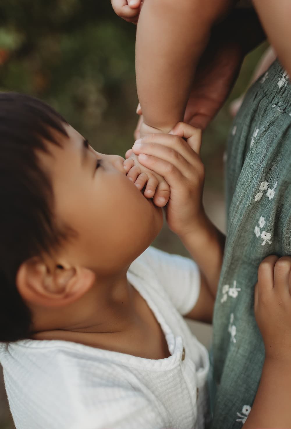 Close-up of a young child kissing a baby's foot during a family photography session in Northern New Jersey.
