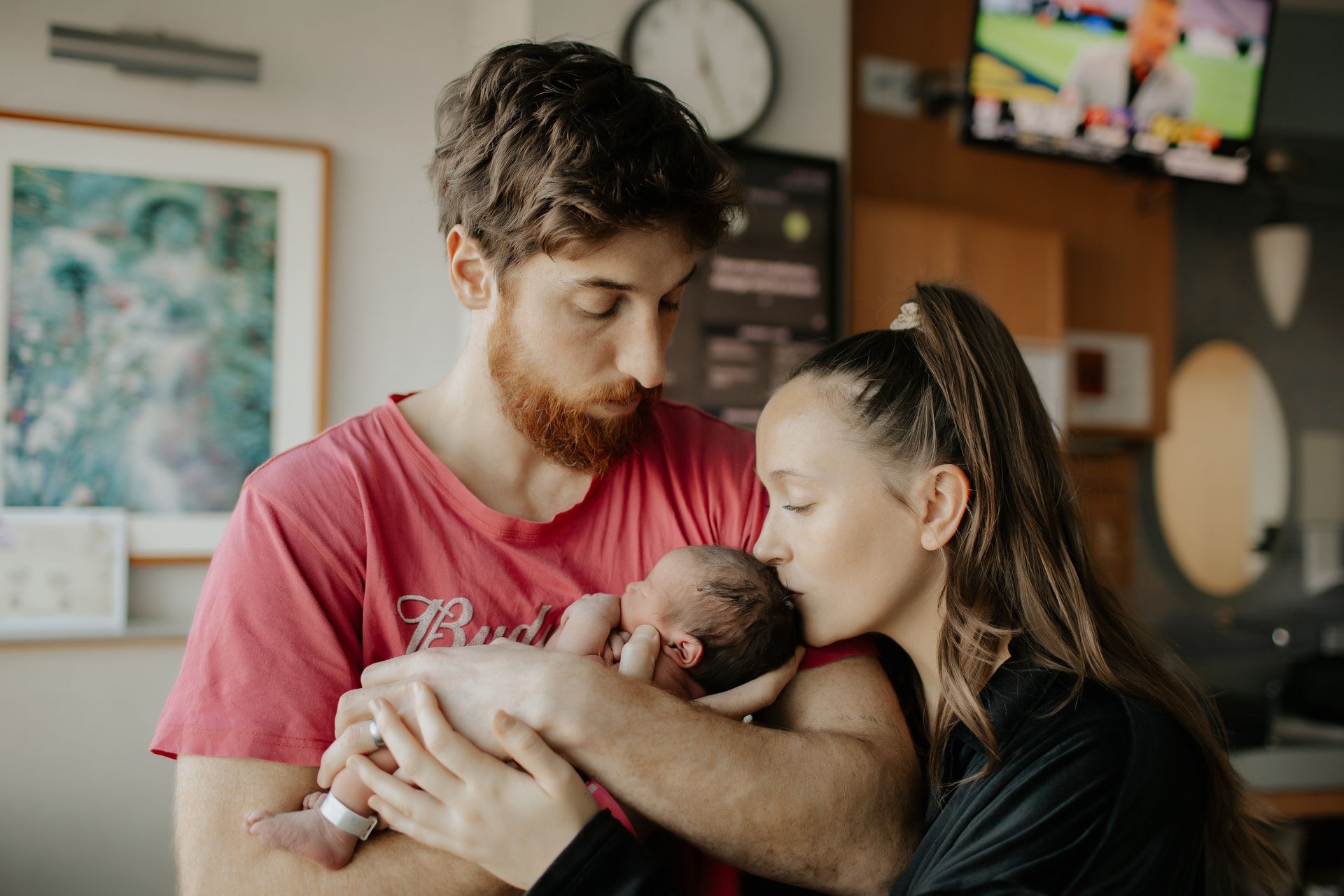 A man and woman are holding a newborn baby in a Morristown Medical Center hospital room.
