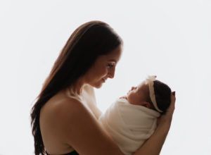 A woman is holding a newborn baby wrapped in a blanket.