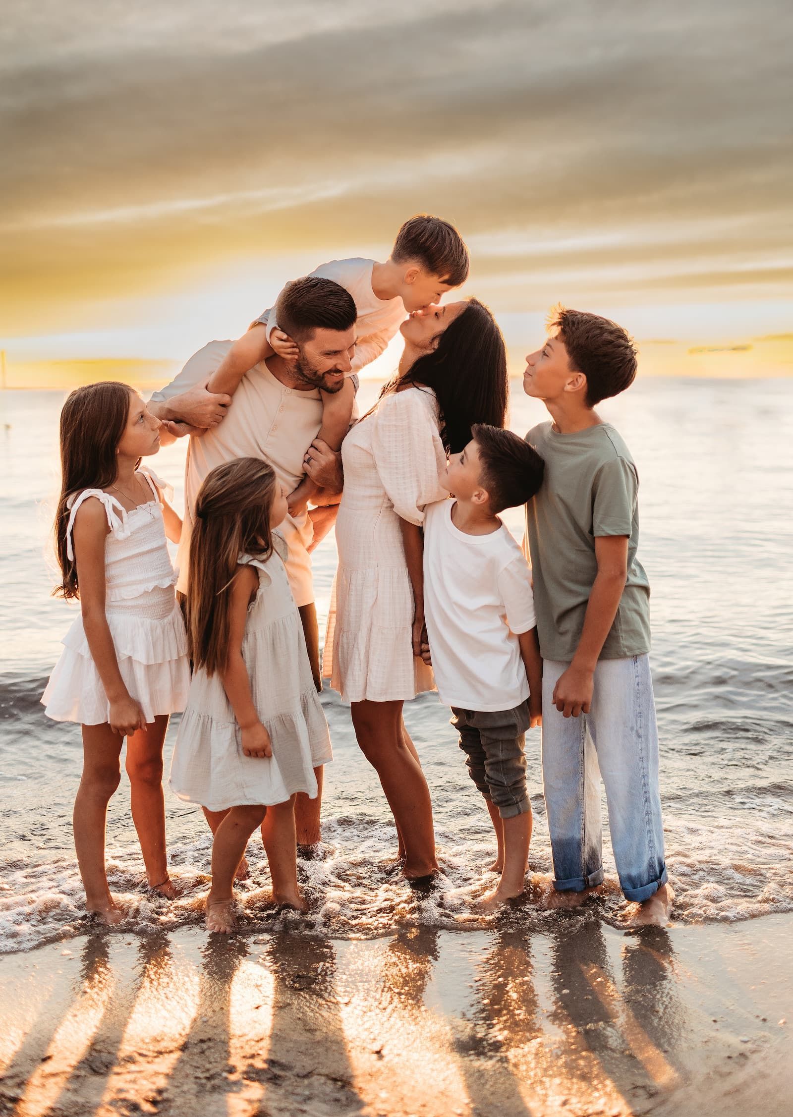 Family of seven sharing a playful moment during a sunset beach photography session in New Jersey.