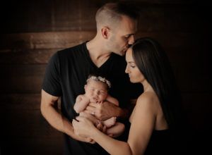 A man and a woman are holding a newborn baby.