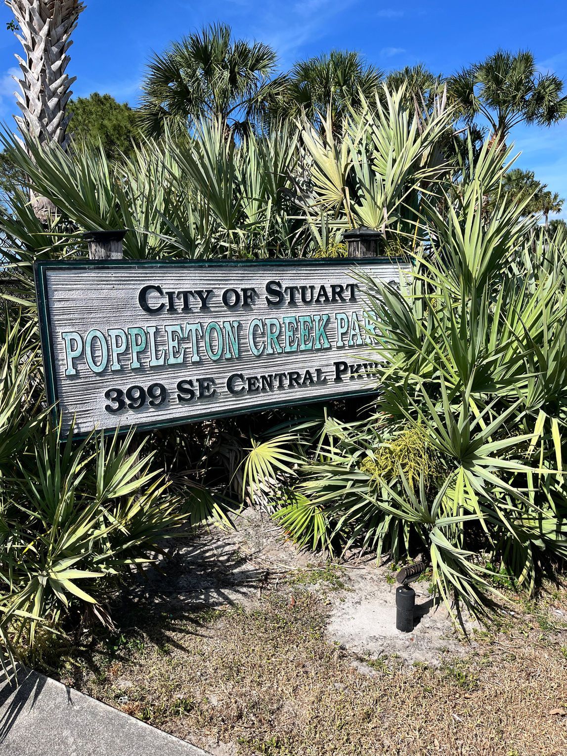 A city of stuart sign is surrounded by palm trees.
