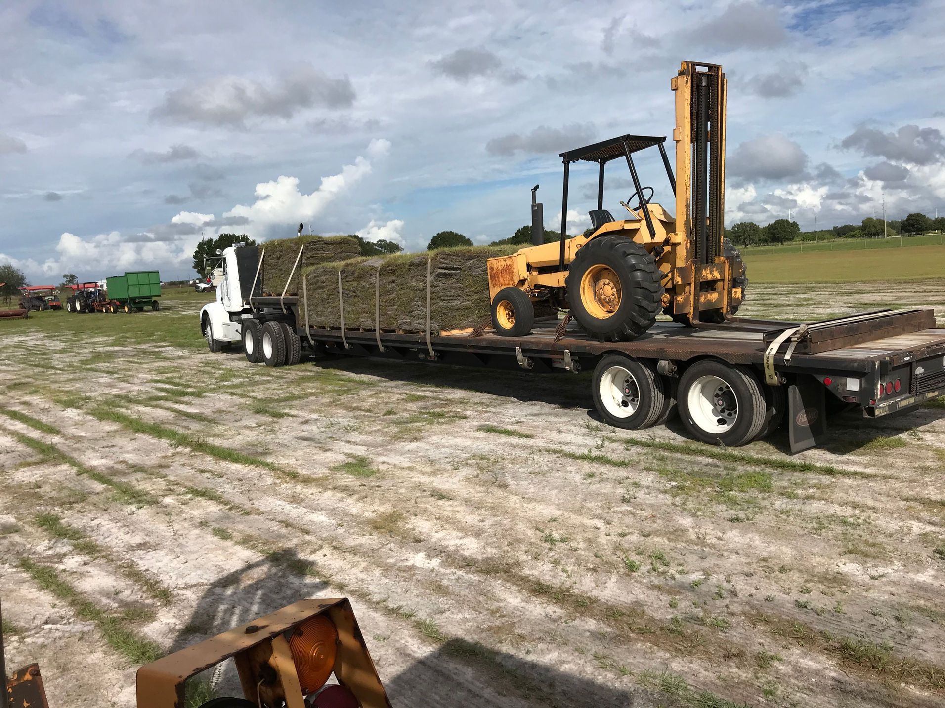 A yellow tractor is sitting on top of a flatbed trailer.