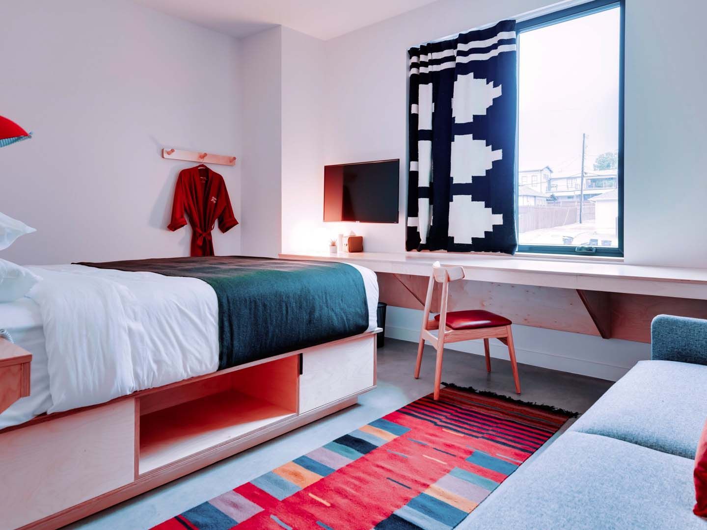 A bedroom with a bed a couch a desk and a window