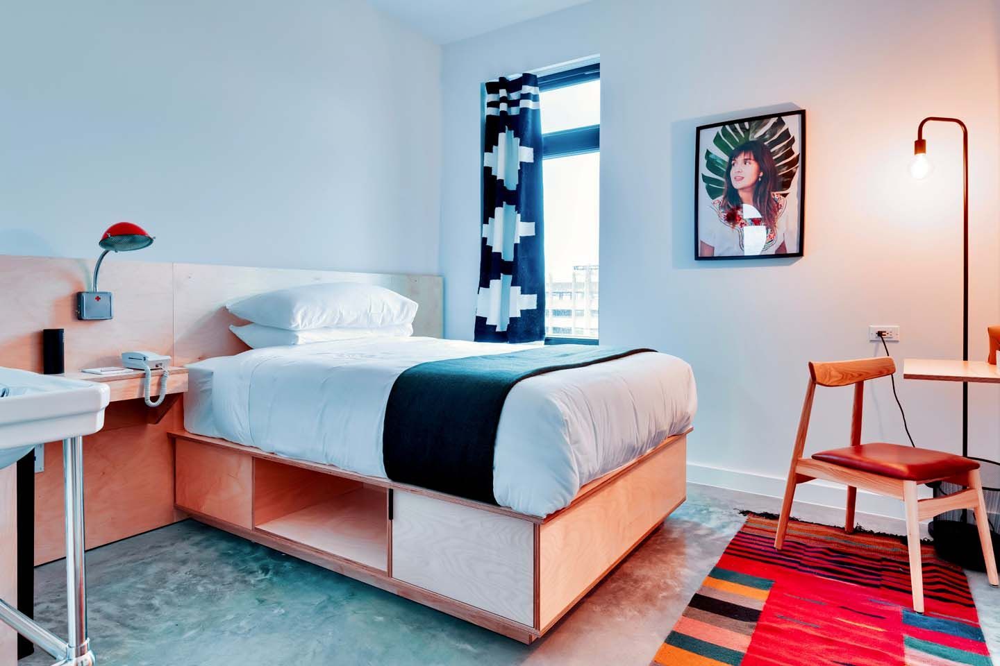 There is a picture of a woman on the wall above the bed in the room.