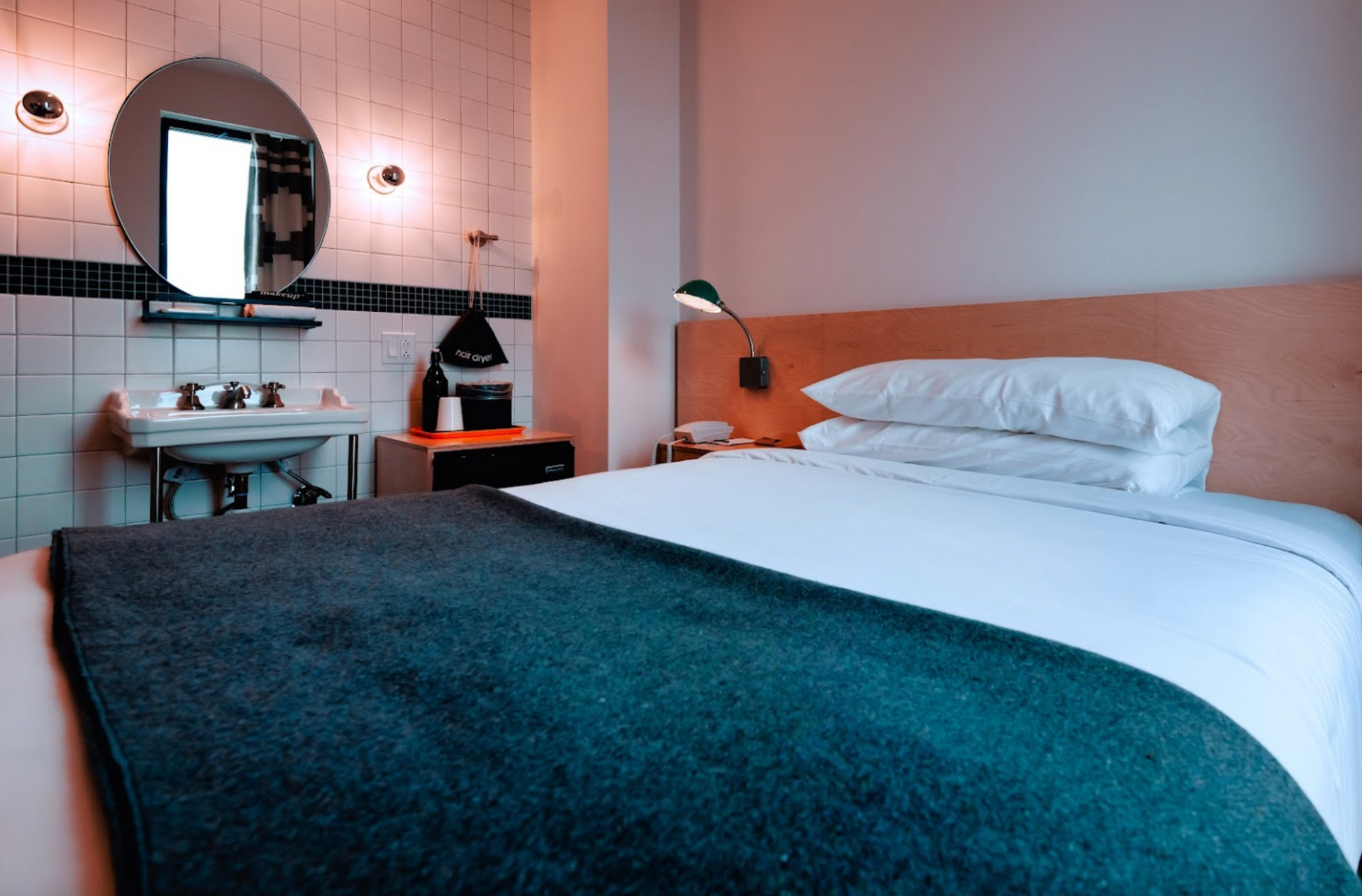 A hotel room with a bed , sink and mirror.