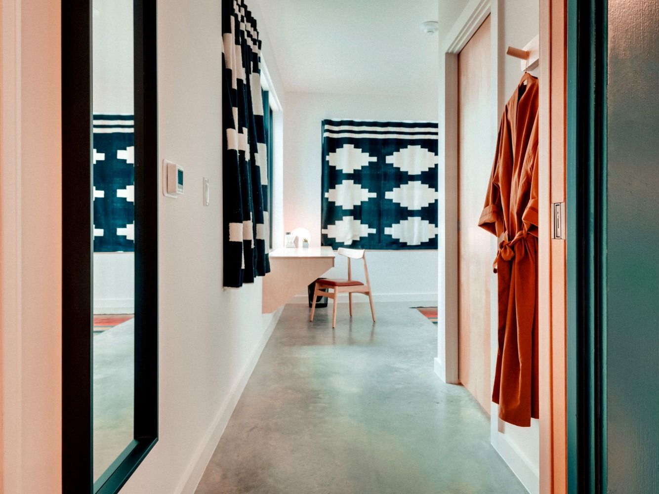 A hallway with a mirror and a robe hanging on the wall.