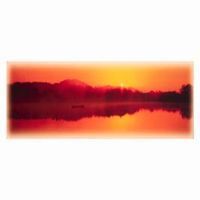 Sunset over lake, silhouetted mountains, orange and red hues.
