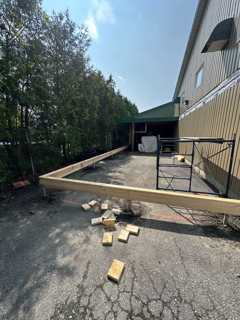Terrasse en bois endommagée à côté d'une maison, avec des briques et des débris éparpillés sur l'allée.