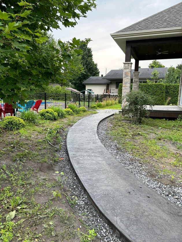 Une allée en béton menant à un belvédère dans une cour arrière.