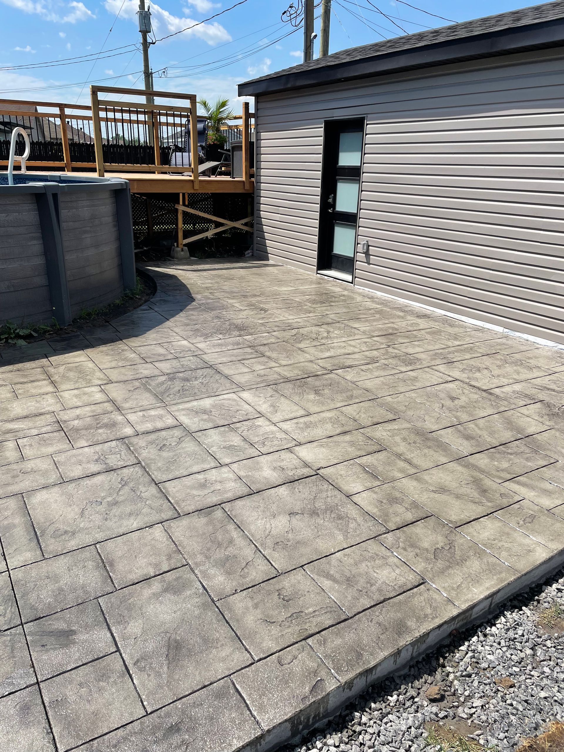 Un patio avec une piscine en arrière plan et une maison en arrière plan.
