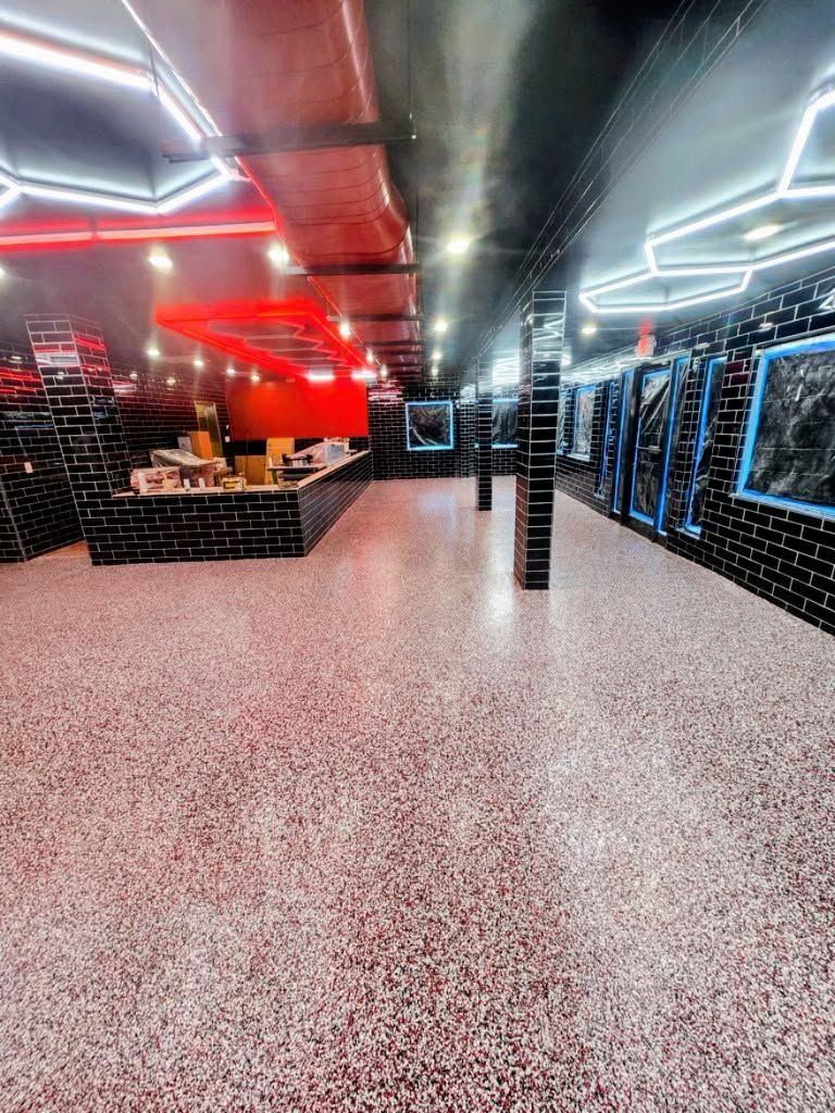 Empty modern lounge with red and blue neon lighting and a speckled terrazzo floor