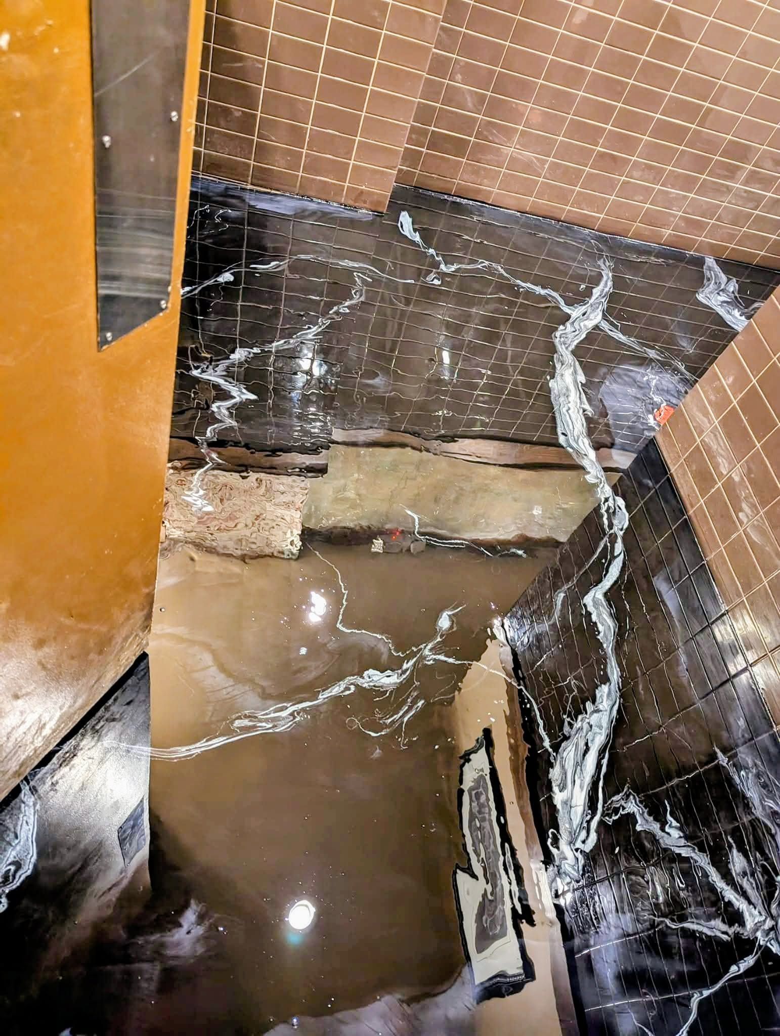 Flooded stairwell with muddy water and wet walls, debris floating on the surface.
