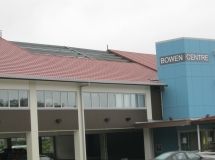 A blue building with a red roof and a car parked in front of it.