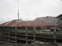 A large building under construction with a crane lifting the roof.