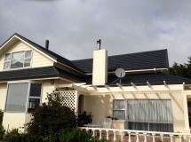 A white house with a black roof and a satellite dish on the roof.