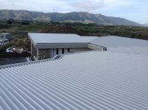 An aerial view of a white corrugated metal roof with mountains in the background.