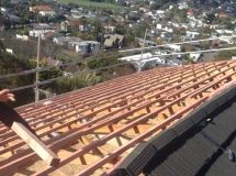 A person is standing on top of a wooden roof.
