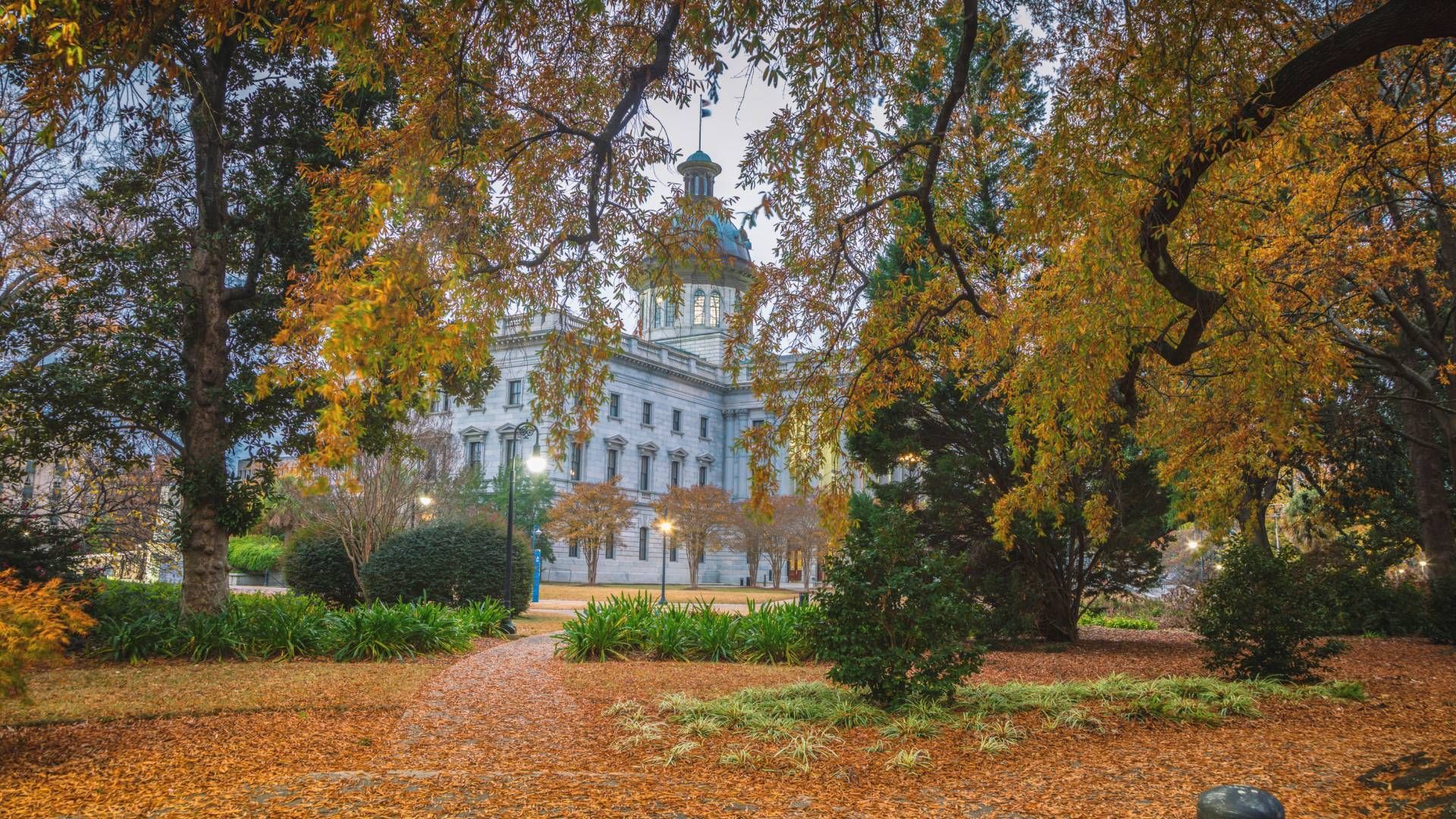 South Carolina State House in Columbia framed by golden autumn foliage along a garden pathway