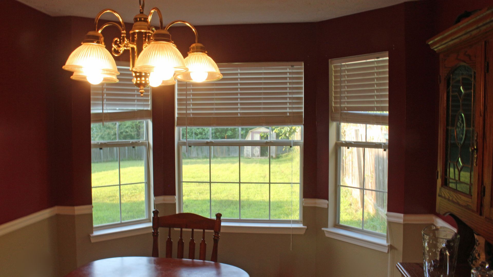 Faux-wood blinds raised on a bay window in a breakfast nook.