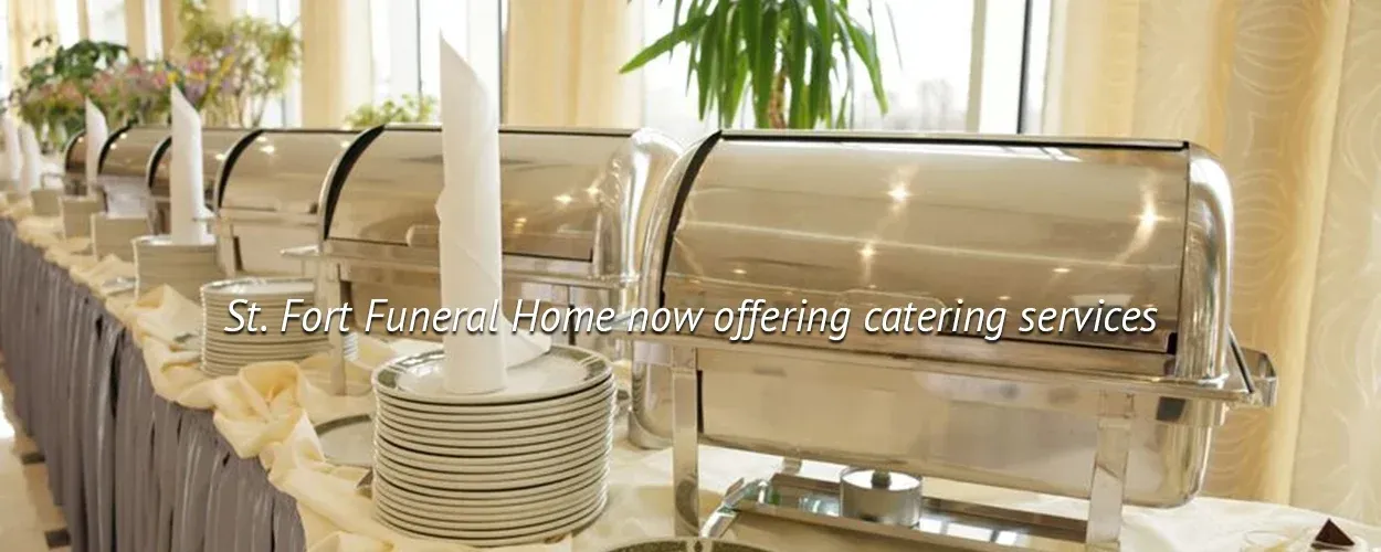 Buffet table with covered dishes and white plates in a bright dining room