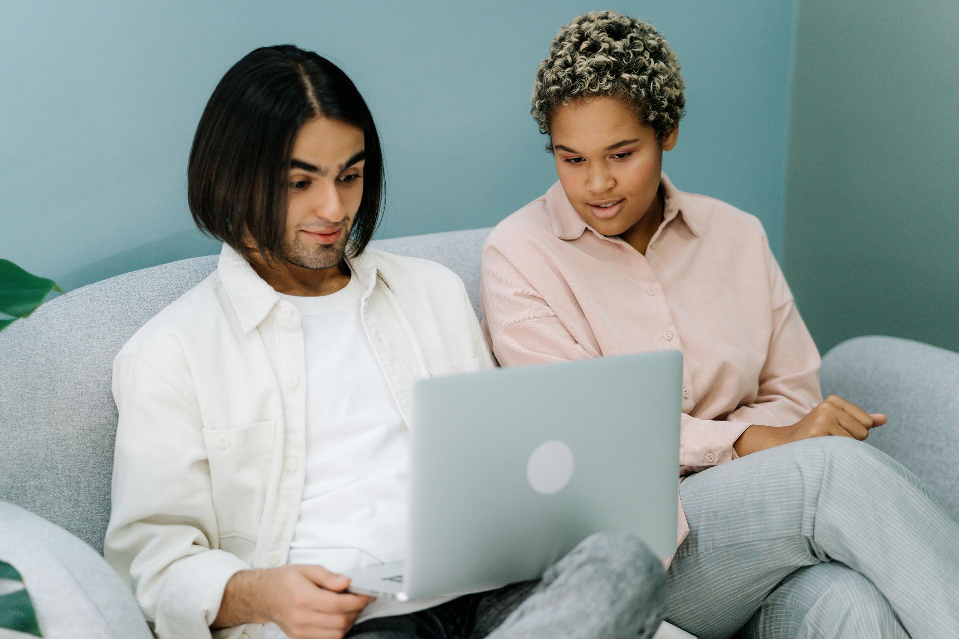 Two people sitting on a couch using a laptop together