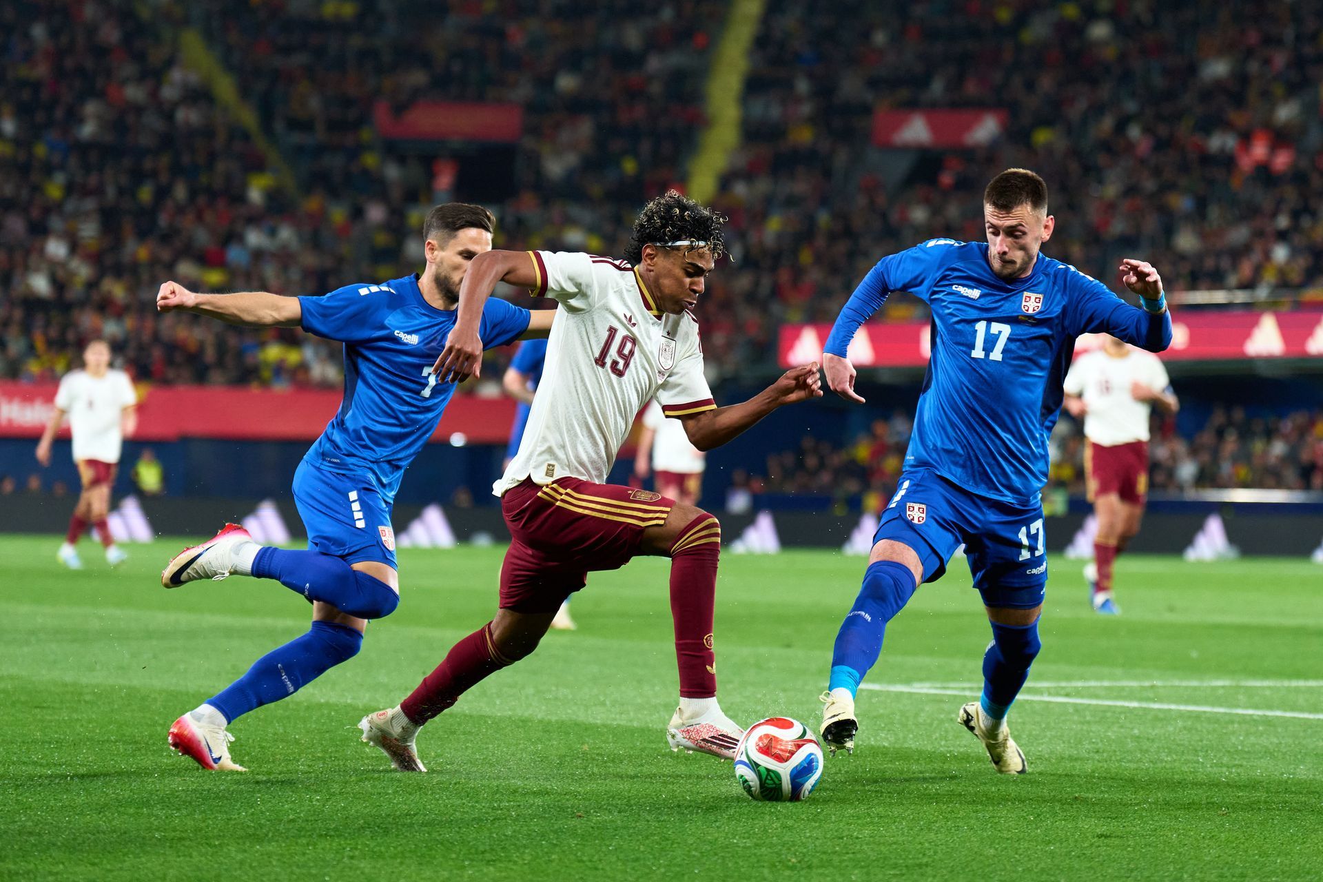 Soccer players in blue and maroon contest the ball on a stadium field during a match