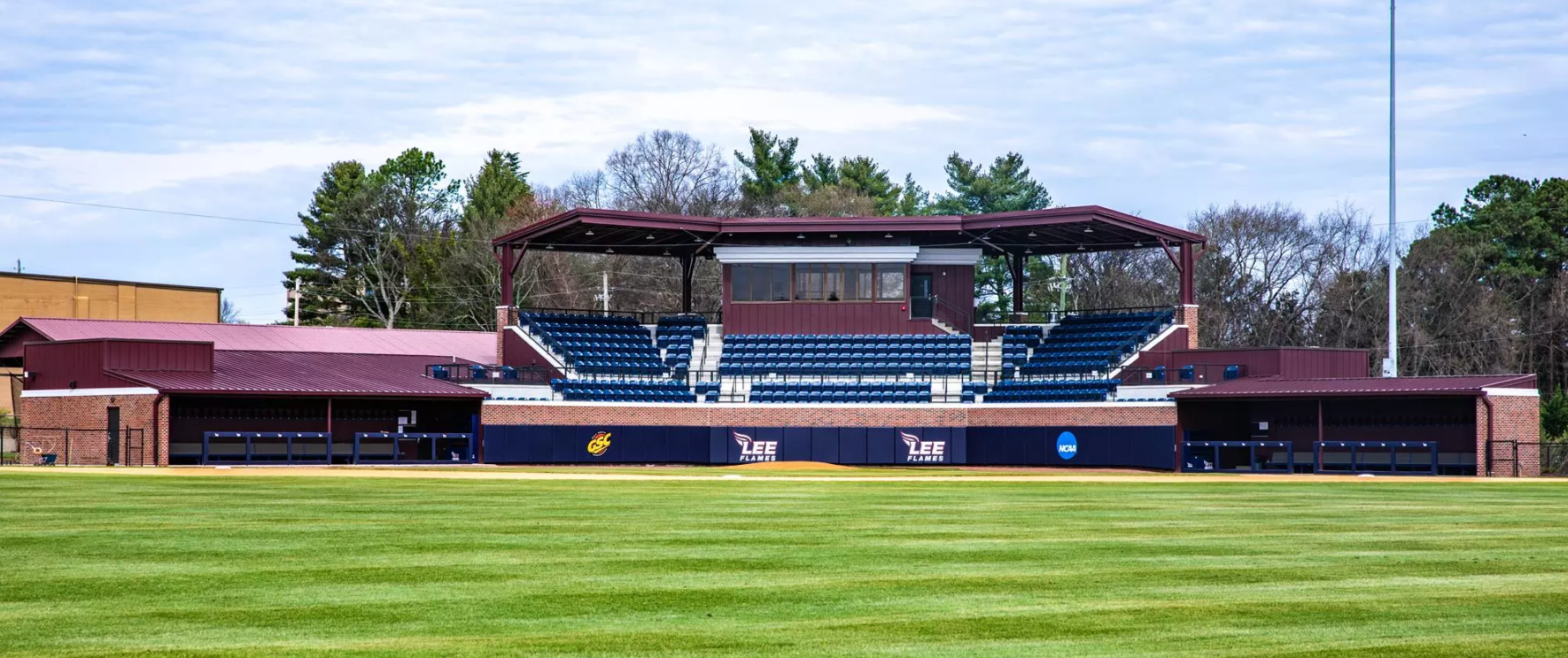 Empty baseball stadium with blue seating and a manicured green field under a clear sky