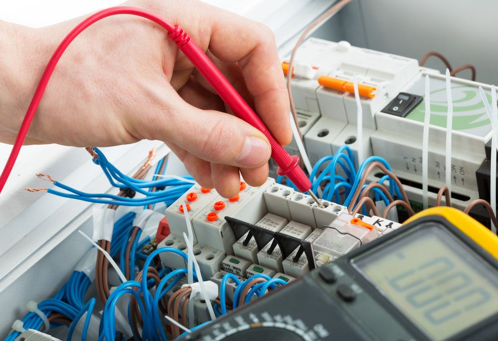 A Man Holds a Red Probe to Test an Electrical Circuit Board — Rabbit Electrical Service In Taminda, NSW