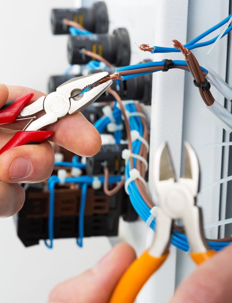 A Man Using Pliers to Strip Blue and Brown Electrical Wires — Rabbit Electrical Service In Taminda, NSW