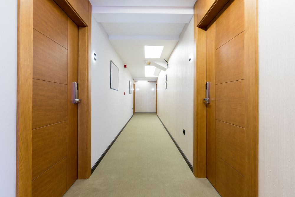 A Long Hallway With Wooden Doors in a Hotel — Rabbit Electrical Service In Gunnedah, NSW