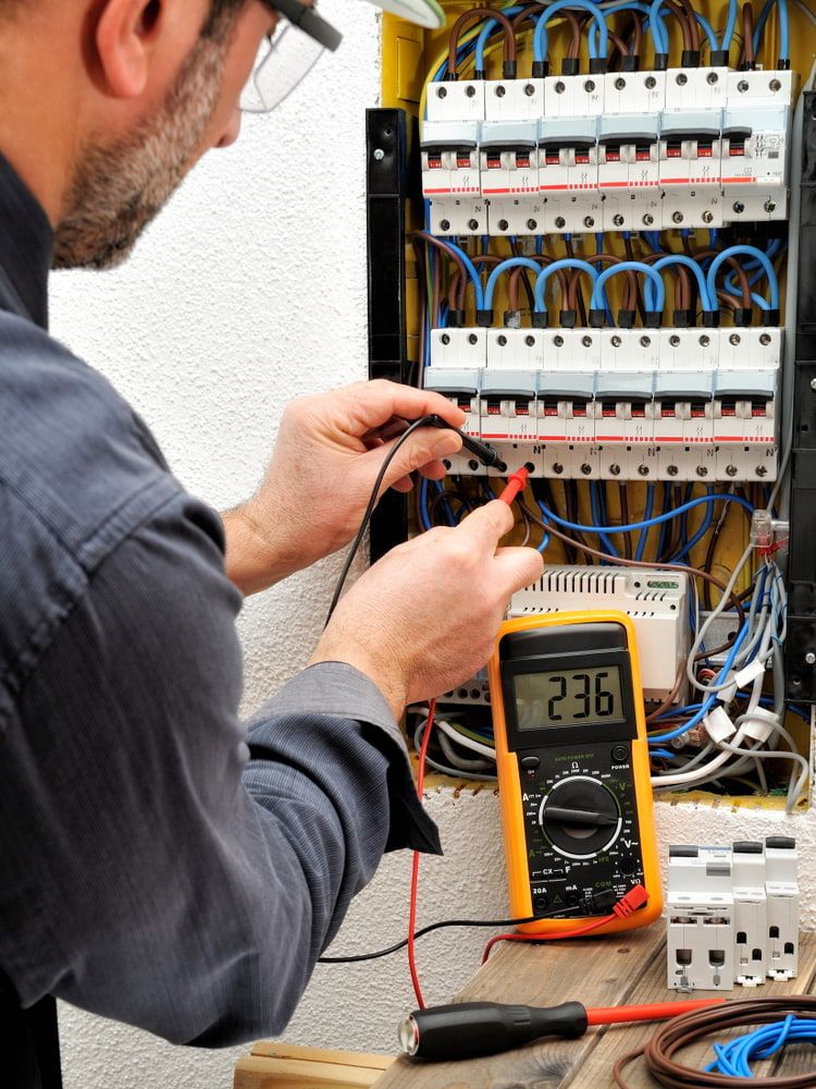 A Man is Using a Multimeter — Rabbit Electrical Service In Narrabri, NSW