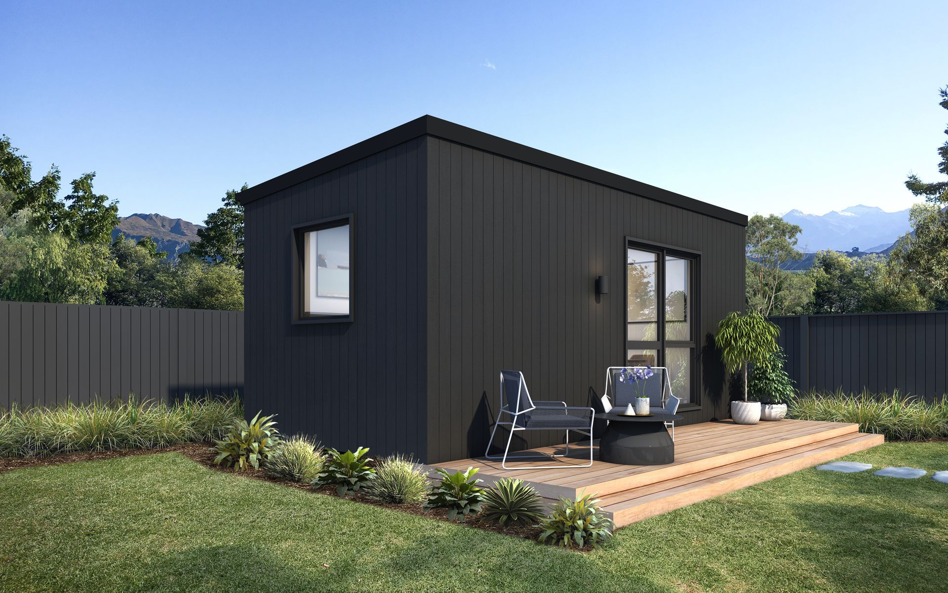 Black modern tiny house with a wooden deck and outdoor seating in a grassy yard