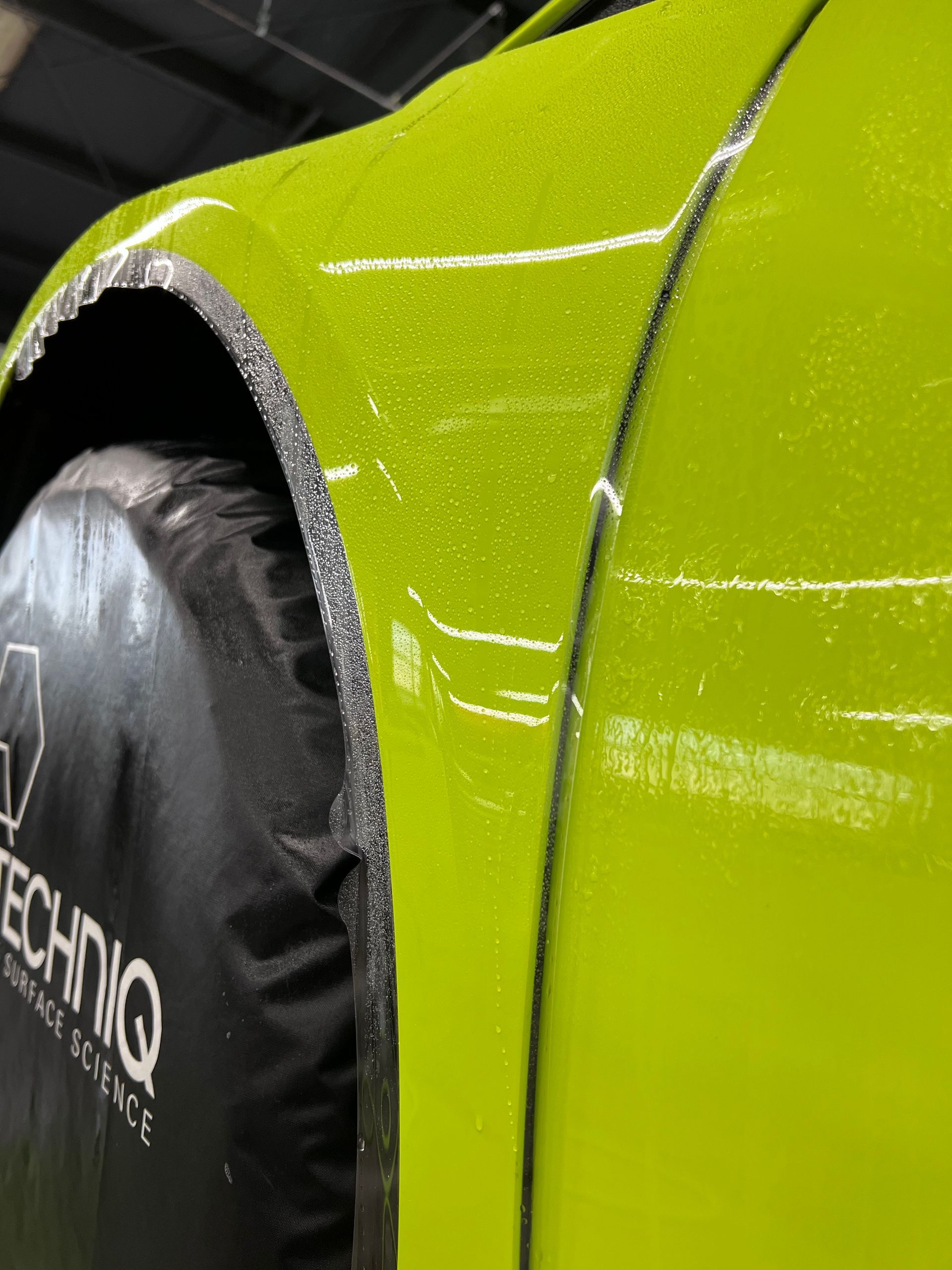 A close up of a green car with a black tire cover on it
