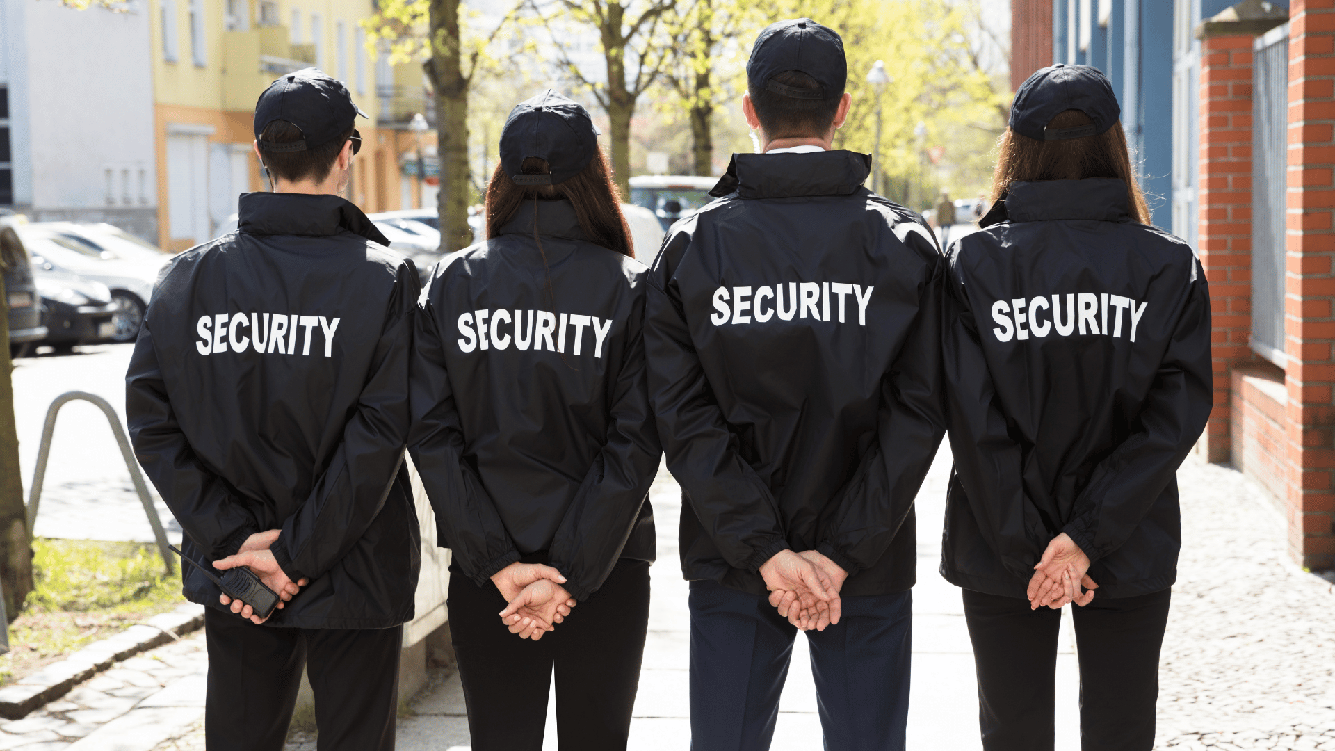 A group of security guards are standing next to each other on a sidewalk.