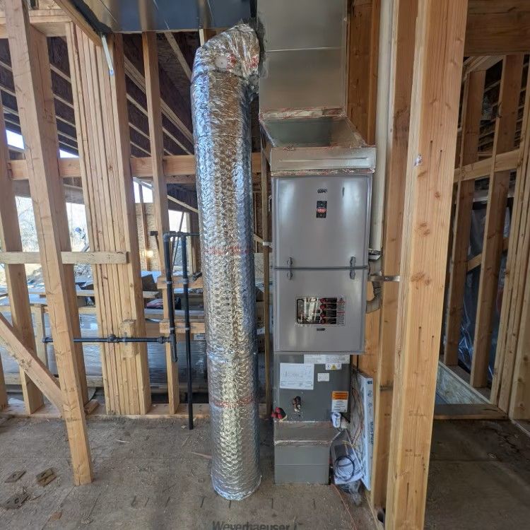 Unfinished home framing with HVAC furnace and shiny ductwork installed in a utility closet